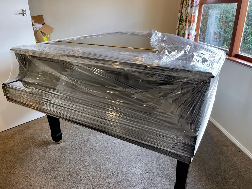 Piano moving in Round Rock, TX showing a newly wrapped piano secured in protective plastic for safe transport